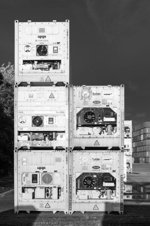 Monochrome image of stacked shipping containers in Hamburg port showcasing industrial shipping and logistics.